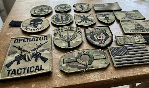 A collection of tactical and military-style OCP patches on a wooden table.
